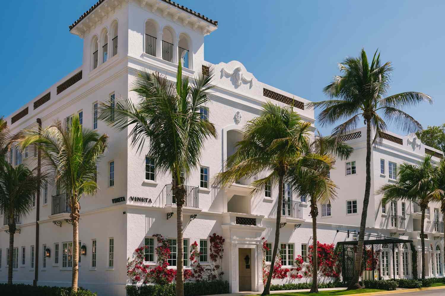 White Spanish-revival hotel in Palm Beach framed by palms